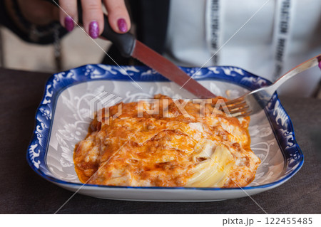 Cutting lasagna food on a plate in a close-up view. 122455485