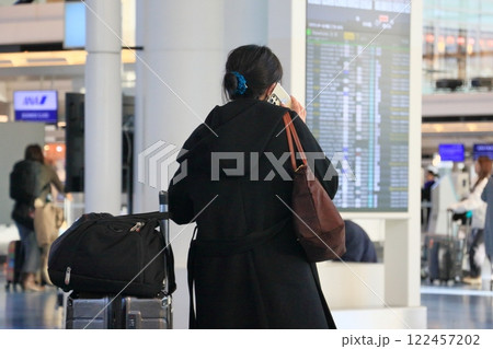 空港ターミナルで電話をかける女性 空港ターミナルで電話をかける女性 122457202