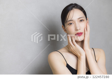 頬に手を当てる若い女性 122457280