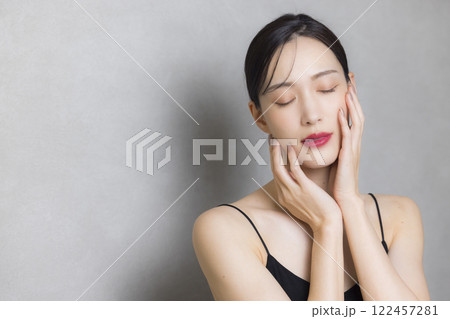 頬に手を当てる若い女性 122457281