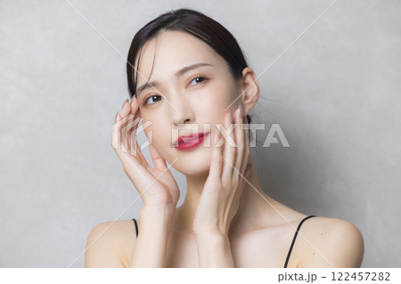 頬に手を当てる若い女性 122457282