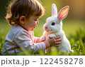 Child playing with white rabbit on green grass, Easter symbol 122458278