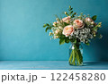 Bouquet of pink flowers in glass vase on blue background with copy space 122458280