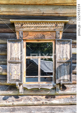 Window of an old traditional Russian wooden house with carved trim and shutters 122458354