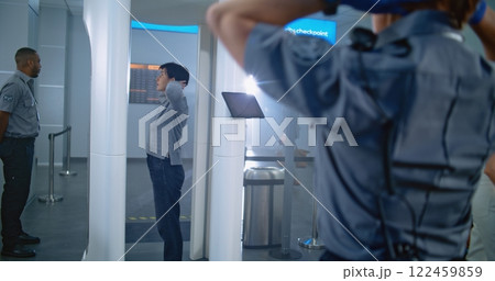 Adult Woman Passes Through Metal Detector Scanner. Female Security Officer Inspects Passenger Adult Woman Passes Through Metal Detector Scanner. Female Security Officer Inspects Passenger 122459859