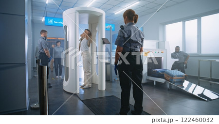 Woman Walks Through Metal Detector Gates. Security Officer Checks Passenger and Documents 122460032