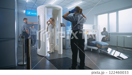 Woman Walks Through Metal Detector Gates. Security Officer Checks Passenger and Documents 122460033