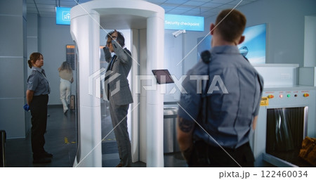 Mature Man Walks Through Metal Detector Gates. Security Officer Checks Passenger, Documents Mature Man Walks Through Metal Detector Gates. Security Officer Checks Passenger, Documents 122460034