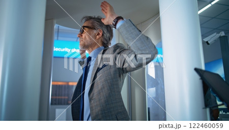 Airport Terminal: Man Passes Through Metal Detector. Security Officer Controls Passenger Inspection 122460059