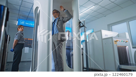 Diverse People Passing Through Metal Detector Gates in Airport Terminal 122460179