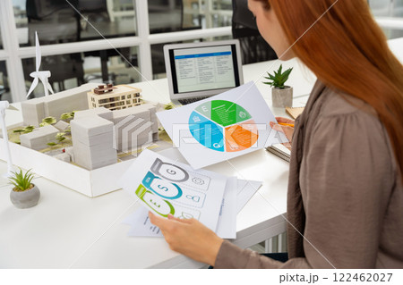 Young female specialist scrutinizing the diagrams of a new project documentation 122462027