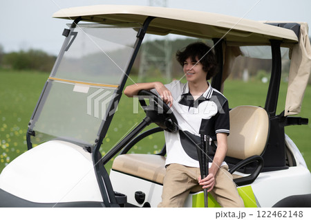 Dark-haired young golfer near the golf cart with brassie 122462148