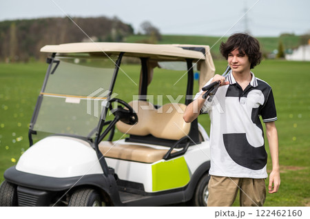 Dark-haired young golfer near the golf cart with brassie 122462160