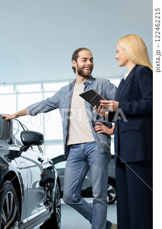 Female consultant talking to a customer in a car showroom Female consultant talking to a customer in a car showroom 122462215