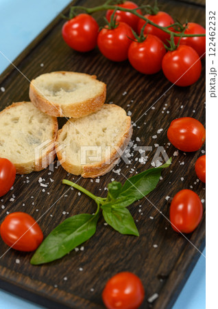 Slices of fresh bread with butter resting on a dark wooden board. 122462232