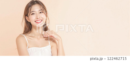 Smiling young woman with flawless skin posing against a pastel background, promoting beauty, skincare, and confidence. 122462715