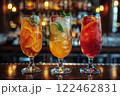 Still life of three bright yellow and red drinks in different glasses on a dark background of the bar counter 122462831