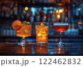 Still life of three bright yellow and red drinks in different glasses on a dark background of the bar counter 122462832