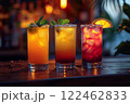 Still life of three bright yellow and red drinks in different glasses on a dark background of the bar counter. 122462833