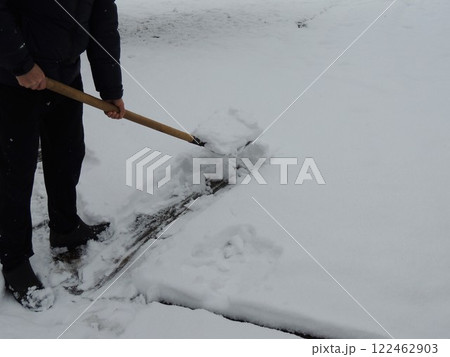 visible lower part of man in dark clothes with shovel busy clearing area after snowfall, clean snow crust and person with hand tool making path visible lower part of man in dark clothes with shovel busy clearing area after snowfall, clean snow crust and person with hand tool making path 122462903