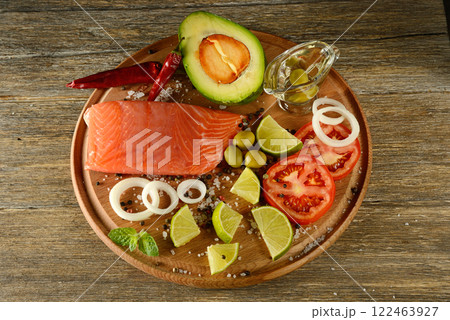 Fresh meat salmon fish, tomatoes, spices, lemon, green olives on kitchen table. 122463927