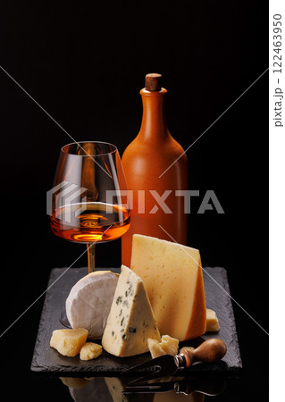 A refined selection of aged cheeses presented on a board, accompanied by a glasses of wine A refined selection of aged cheeses presented on a board, accompanied by a glasses of wine 122463950
