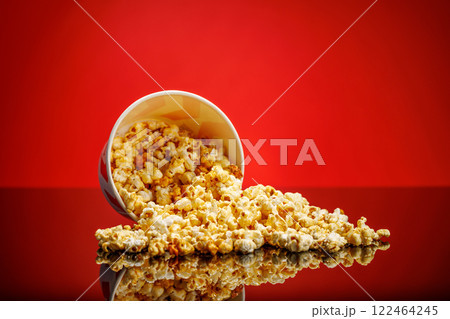 A box of fluffy popcorn against a vibrant red background A box of fluffy popcorn against a vibrant red background 122464245