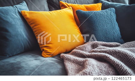 Close-up of living room sofa with vibrant yellow and blue textured throw pillows 122465173
