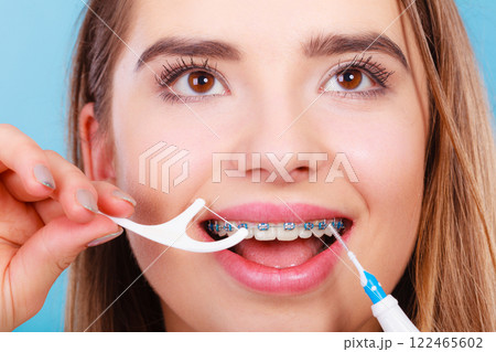 Woman smiling cleaning teeth with braces 122465602
