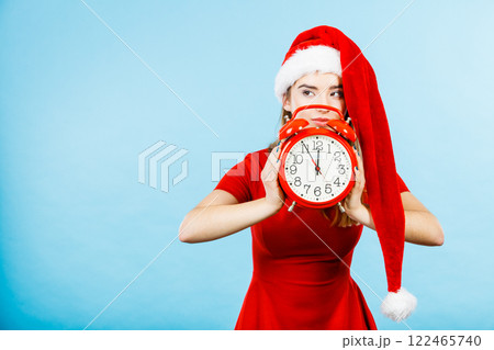 Woman wearing Santa Claus costume holding clock Woman wearing Santa Claus costume holding clock 122465740