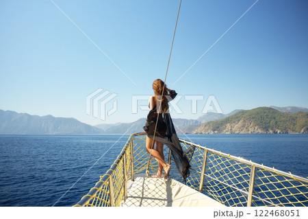 Woman in black bikini admiring ocean view from a yacht  122468051