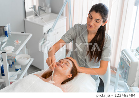 Massage therapist applying face mask to woman with Massage therapist applying face mask to woman with 122468494
