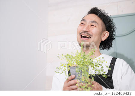 観葉植物を持つエプロン姿の男性 花屋や趣味の園芸イメージ いらっしゃいませ~と見上げる 観葉植物を持つエプロン姿の男性 花屋や趣味の園芸イメージ いらっしゃいませ~と見上げる 122469422
