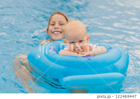 An older brother swims in a pool alongside his baby sibling, who is safely seated in an inflatable float. Joyful family moment full of laughter, bonding, and summer fun. Childhood, care, and sibling 122469447