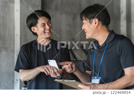 パーソナルトレーニングでカウンセリングを受ける若いアジア人男性とパーソナルトレーナーの男性 122469854