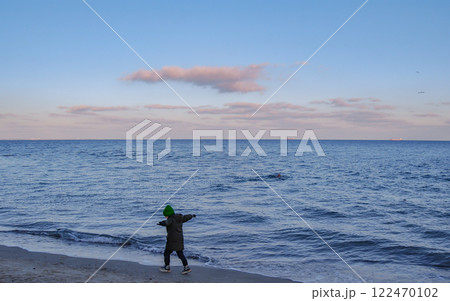 The child feels unity with nature. A little boy, arms outstretched, runs joyfully along the surf line. 122470102