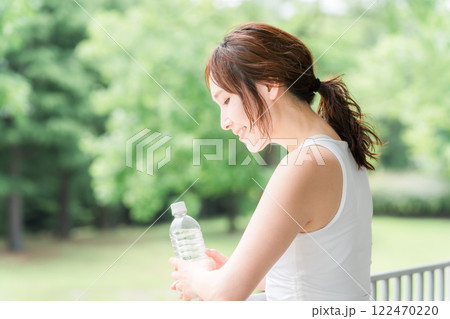 公園・森林の中でミネラルウォーターを飲む若いアジア人女性 122470220