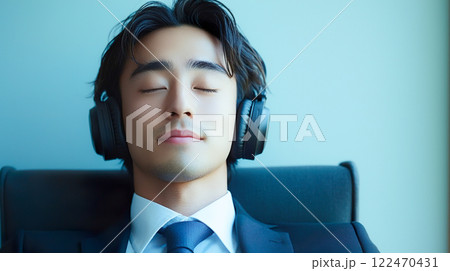 ヘッドフォンで音楽を聴くリラックスした表情のスーツ姿の男性 122470431
