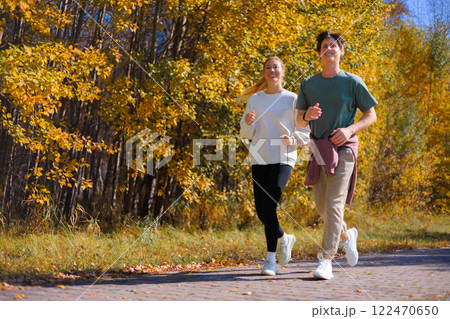 Sporty family couple morning jogging in city autumn beautiful park. Young active man, woman runners 122470650