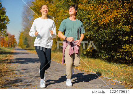 Sporty family couple morning jogging in city autumn beautiful park. Young active man, woman runners 122470654