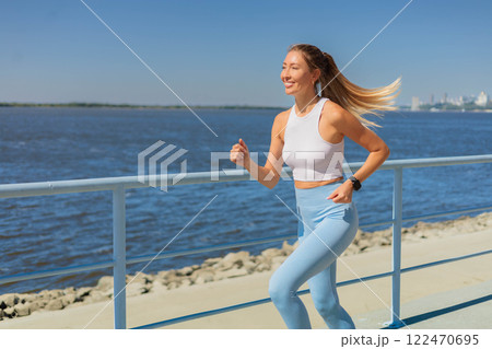 Sport woman morning running jogging on city river embankment side view Sport woman morning running jogging on city river embankment side view 122470695