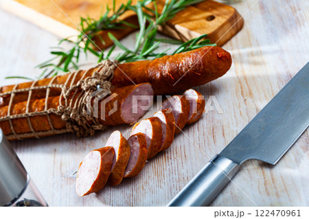 Sliced half-smoked sausages on wooden table 122470961