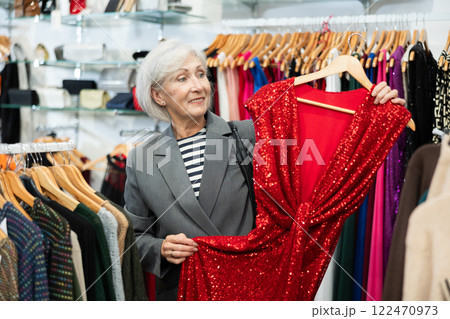 Elderly woman choosing dress in store Elderly woman choosing dress in store 122470973
