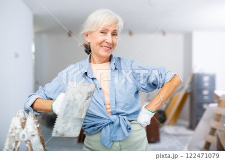 Portrait of positive woman with spatula in her hand in room being renovated 122471079