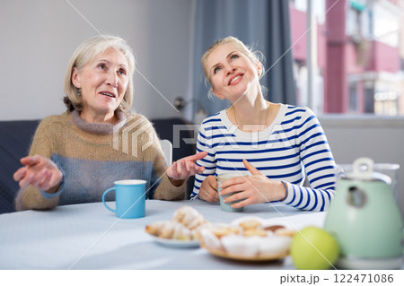 Mature mother and her adult daughter drink tea and chat 122471086