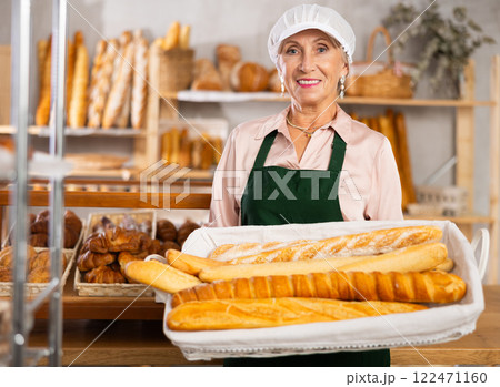 Smiling mature female seller showing assortment of bakery Smiling mature female seller showing assortment of bakery 122471160