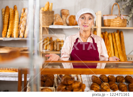senior bakery worker sells croissants and shows off a variety of crescent-shaped buns. senior bakery worker sells croissants and shows off a variety of crescent-shaped buns. 122471161