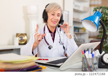 Female doctor in headphones with microphone consults patient on Internet Female doctor in headphones with microphone consults patient on Internet 122471166