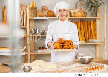 Senior female baker worker show croissants 122471188