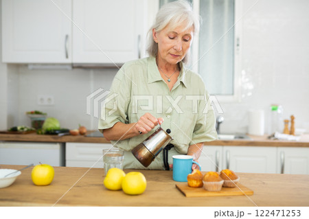 Relaxed elderly woman drinking coffee at kitchen Relaxed elderly woman drinking coffee at kitchen 122471253